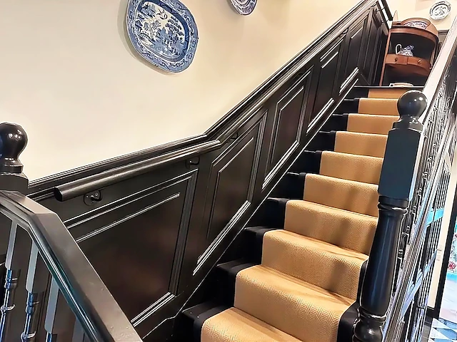 Black panelled staircase wall with a woven herringbone stair runner