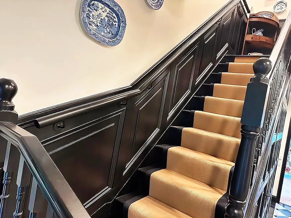 Staircase with black panelled walls and a herringbone stair runner