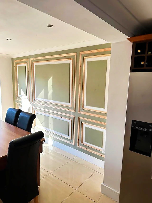 Sage green wall panelling part-way through installation, raw pine mouldings not yet painted